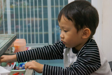 A young Asian child thoughtfully focused while holding objects