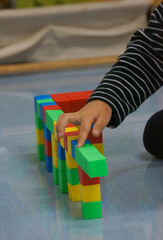 A child's hands building a structure using colorful blocks. This scene highlights creativity, learning, and play with colorful blocks.