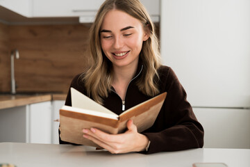 Portrait of Smiling woman reading personal diary in the kitchen