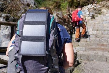 Tourist with solar panel on his backpack goes trekking in mountains of Nepal.
