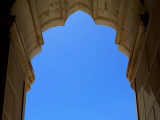 Un arco in stile gotico-moresco incornicia il cielo azzurro.