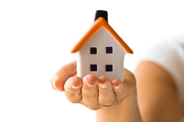 Hand holding detailed house model, symbolizing homeownership and property value.