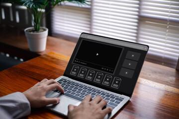 Hands typing on a laptop displaying a video player interface, representing digital media streaming, online video editing workflow, and modern multimedia content management in a creative workspace.