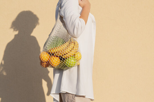 Woman carrying eco bag on shoulder with fruits (horizontal)