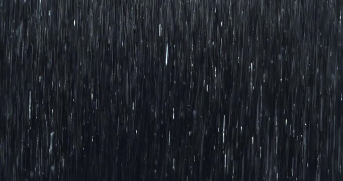 Heavy rain pours down in a dense curtain against a pure black screen, splashing close-up detail. Practical loopable rainfall footage ideal for VFX inserts, storm scenes, and dramatic atmospheres