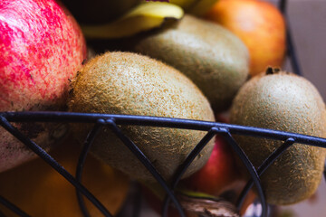 Kiwi, pomegranate and other fruits in a metal basket
