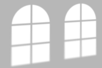 Gentle arch window light casts soft grid shadows on a clean, minimalist gray wall background.