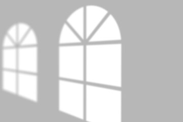 Sunlight cast by arched windows creates dramatic shadow patterns on a clean, modern wall.