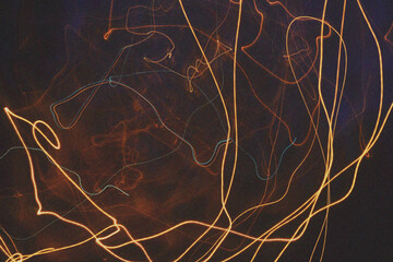 Abstract flowing golden light trails against a dark textured background creating a sense of movement and energy