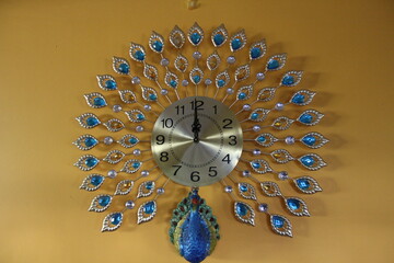 peacock shaped clock hanging on a yellow wall