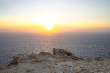 sea sunset view from rocky cliff. aegean sea at sunset. warm pastel tones. minimalistic sea background with copy space 