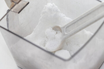 プラスチック容器の中の白砂糖と小さじ