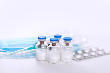 A still life of medical syringes and medication vials. Disposable syringes, medical masks, and fever pills. Supplies for injections and virus protection. 