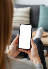 Woman relaxing at home using a smartphone with a blank white screen for app or website mockups and digital marketing campaigns now available