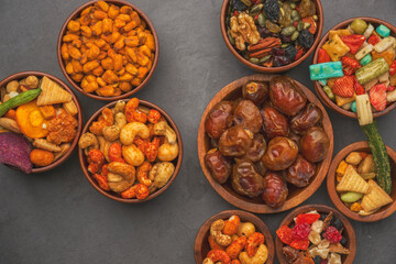 A variety of nuts and dried fruit are displayed in bowls on a counter.
