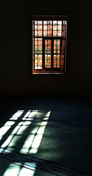 03.03.25 Istanbul. T&uuml;rkiye.The interior of Shehzade Ahmed's turban in Bursa. A window with a lattice, a light pattern on the carpet, a dark hall. Vertical composition; religious architecture.