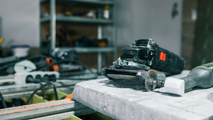 Angle grinder and tools on a stone surface in a workshop setting