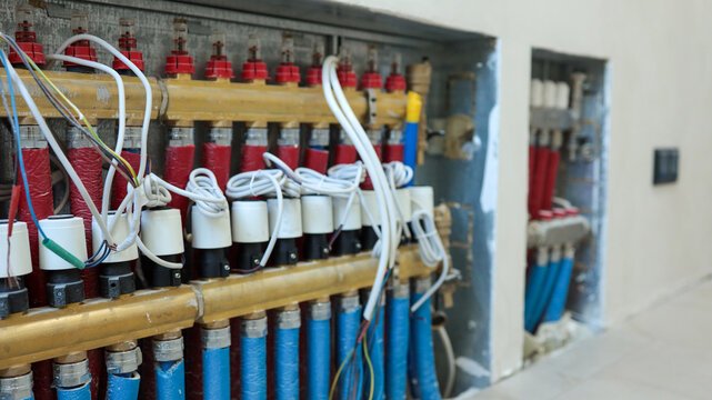 Close-up of a radiant floor heating manifold system with pipes and wiring