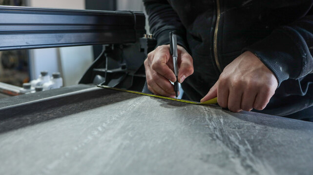 craftsman measuring and marking a surface with a tape measure and pen - Powered by Adobe