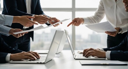 Corporate team collaborating on a project, analyzing data on papers and laptops during a strategic business meeting