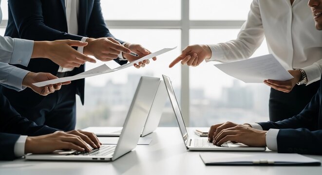 Corporate team collaborating on a project, analyzing data on papers and laptops during a strategic business meeting - Powered by Adobe