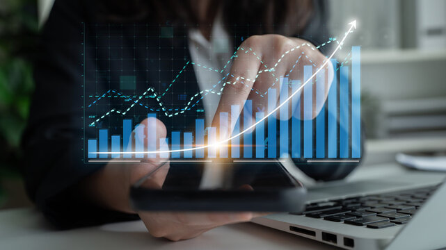 A business professional interacts with a smartphone displaying financial analysis, while digital growth charts illustrate trends in a modern office setting. Impute - Powered by Adobe