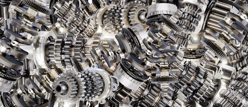A panoramic background wallpaper of car parts. A collection of metal mechanical engine components, such as the gearbox and crankshaft from an internal combustion engine. Light shines through the parts