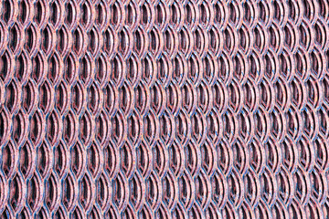 close-up view of a textured metal surface with a repeating pattern of oval shapes. The color is a mix of red and silver tones, creating a modern industrial look