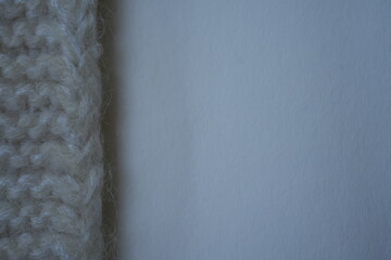 white Minimalist background combining a strip of knitted wool fabric on the left and smooth beige paper on the right. The clean composition creates a natural, warm backdrop suitable for text placement