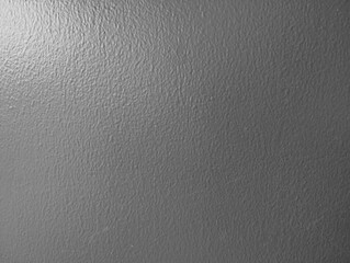 左上から自然光が当たる濃いグレーのザラ付きのある壁面