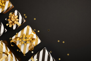White and black striped gifts with golden ribbons on black background. Space for text, congratulations, wishes.