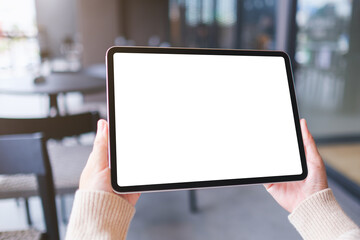 Mockup image of a woman holding digital tablet with blank white desktop screen in cafe