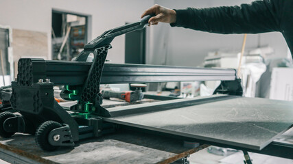 Cutting a large tile with a professional tile cutter in a workshop setting