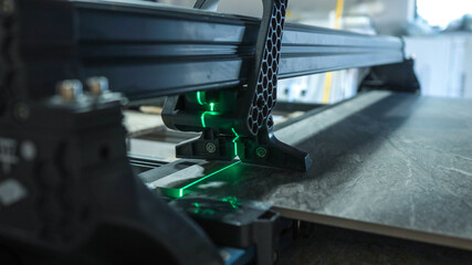 Close-up of a tile cutter with a laser guide cutting a large tile