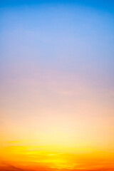 Sunset or sunrise sky with a vibrant gradient of orange, gold, and soft blue. Clear atmosphere with wispy clouds. Peaceful, natural light background. hope, freedom, new day Concepts, Vertical