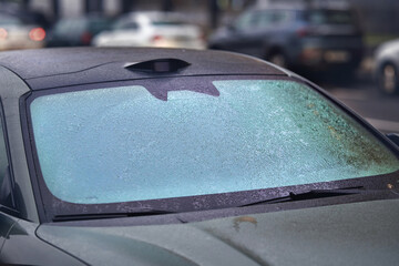 Car windshield completely covered in icy droplets after freezing rain, poor visibility and the cold winter weather effects that impact everyday driving safety. Frozen rain droplets. Selective focus