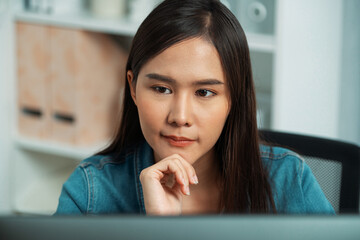 Working young beautiful asian creative manager focusing on pc, creating with new website design on new social media online channel planning with blue jeans shirt at modern home office. Stratagem.