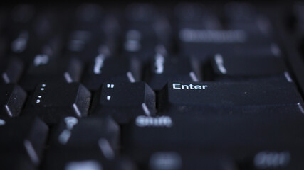 Enter key on dark keyboard — technology background with shallow depth of field