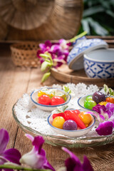 A beautifully arranged selection of colorful Thai Luk Chup—miniature fruit-shaped mung bean desserts—presented in small ceramic bowls with traditional blue-and-white patterns. 