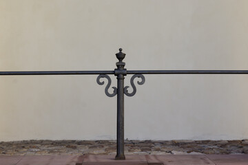 Metalowa dekoracyjna balustrada na tle jasnej ściany, minimalistyczny architektoniczny detal.