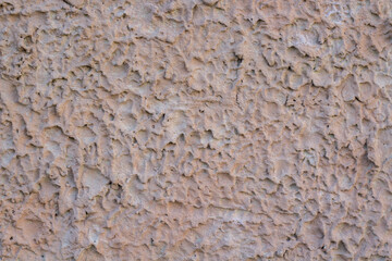 Chropowata tynkowana ściana w beżowym kolorze, strukturalna tekstura elewacji.