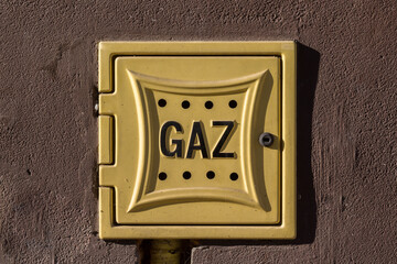 Żółta skrzynka gazowa na ścianie budynku, detal miejskiej instalacji.