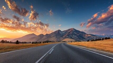 Asphalt road winding through mountain landscape under dramatic sky clouds at sunrise with soft morning light illuminating nature scenery