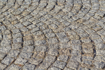 Kamienna kostka brukowa ułożona w łukowaty wzór, tekstura nawierzchni ulicznej.