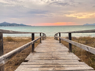 Obraz premium A wooden bridge leads to the beach playa de muro in majorca