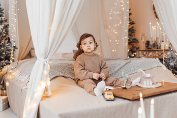 Little boy playing with a toy. Child is sad sitting on the bed. Brown colors.