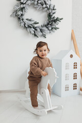 Little boy playing with toy horse. Child swinging on a rocking horse on a white background