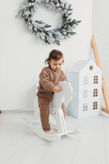 Little boy playing with toy horse. Child swinging on a rocking horse on a white background
