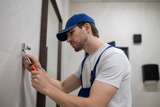 Worker in uniform installing hygiene device in public restroom
