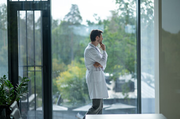 Male doctor looking thoughtfully out of window